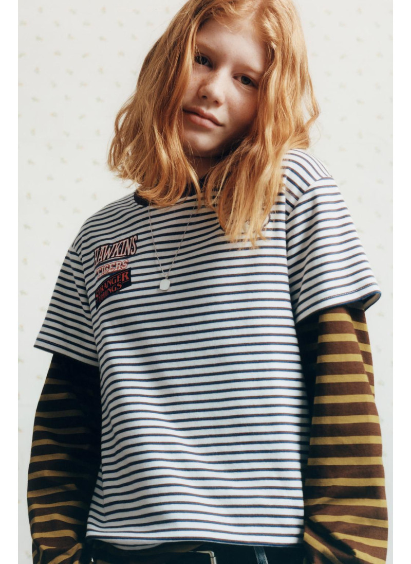 ФУТБОЛКА В ПОЛОСКУ STRANGER THINGS © NETFLIX ФУТБОЛКА В ПОЛОСКУ STRANGER THINGS © NETFLIX